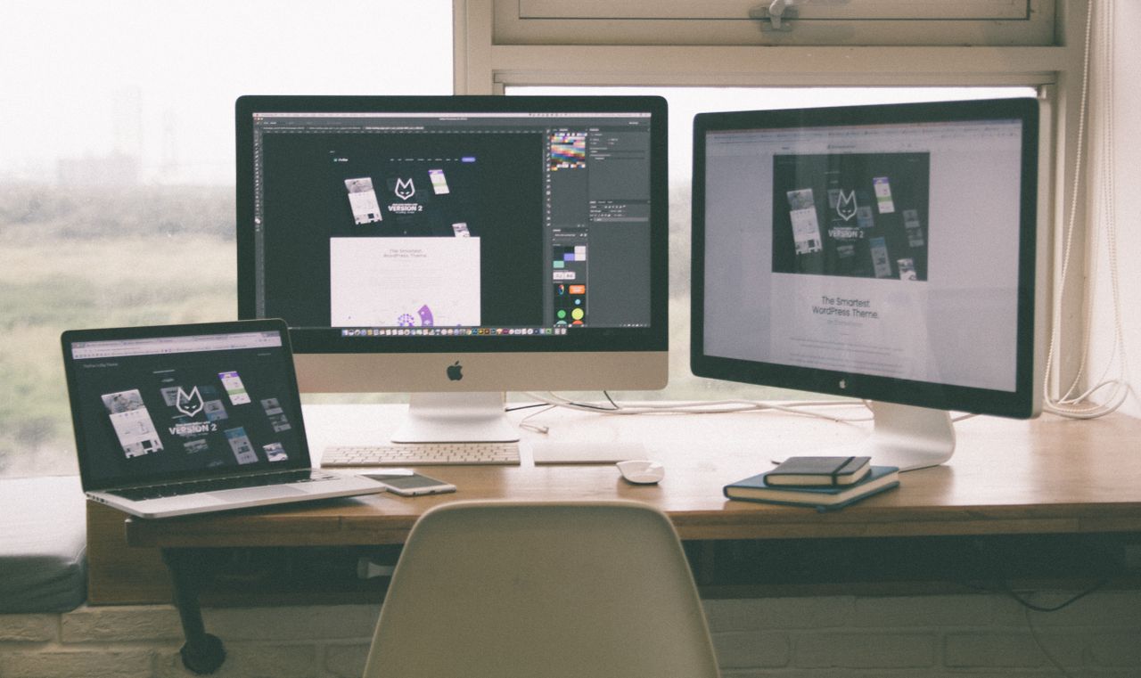 services-02 Stylish and efficient workspace with multiple monitors, laptop, and smartphone, showcasing a web design project.